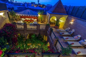 A rooftop terrace with lounge chairs, a covered seating area, and potted plants. - Riad Samsli (Marrakech)