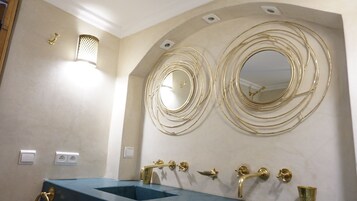 A bathroom with two sinks, gold fixtures, and a decorative mirror with concentric circles.