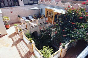 Ein Dachgarten mit Sitzgelegenheit, einer Holzpergola und Topfpflanzen.