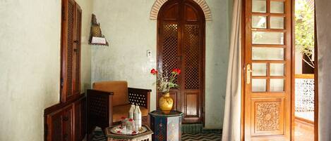 A traditional room with a wooden door, a small table with a vase of flowers, and a chair.