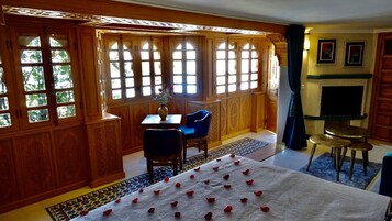 Ein Zimmer mit Holzwandverkleidung, einem Esstisch mit Stühlen, einem Fernseher und einem gemusterten Teppich.
