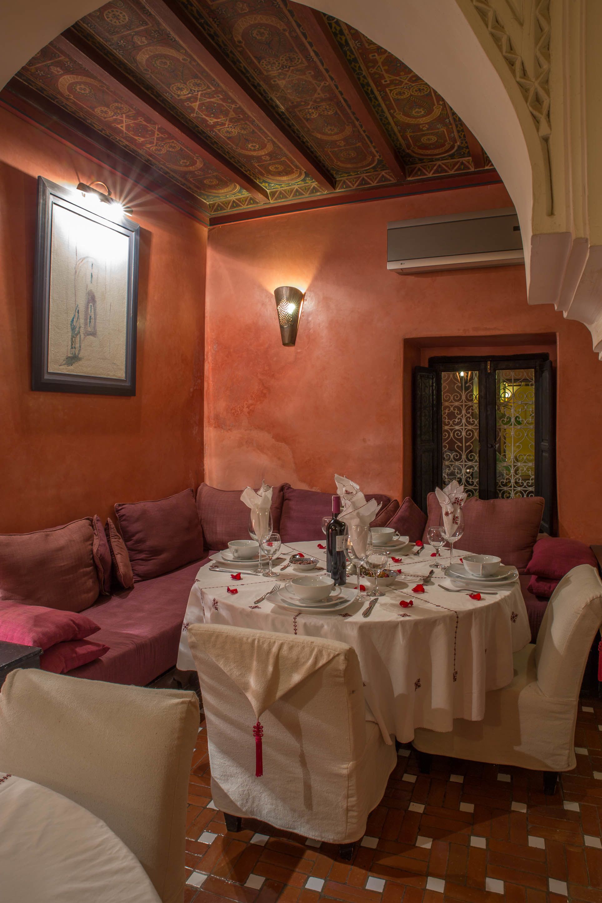 A dining area with a round table set for four, surrounded by cushioned seating.