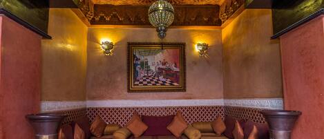 A traditional Moroccan interior with a patterned sofa set, a central table, and large vases.