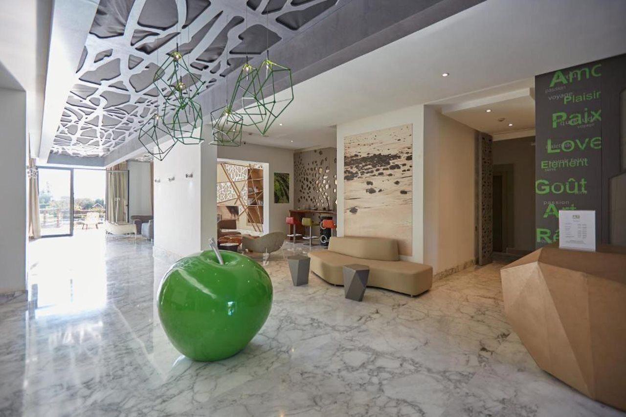 A modern lobby with a large green sculpture, a geometric ceiling design, and a wall with text.