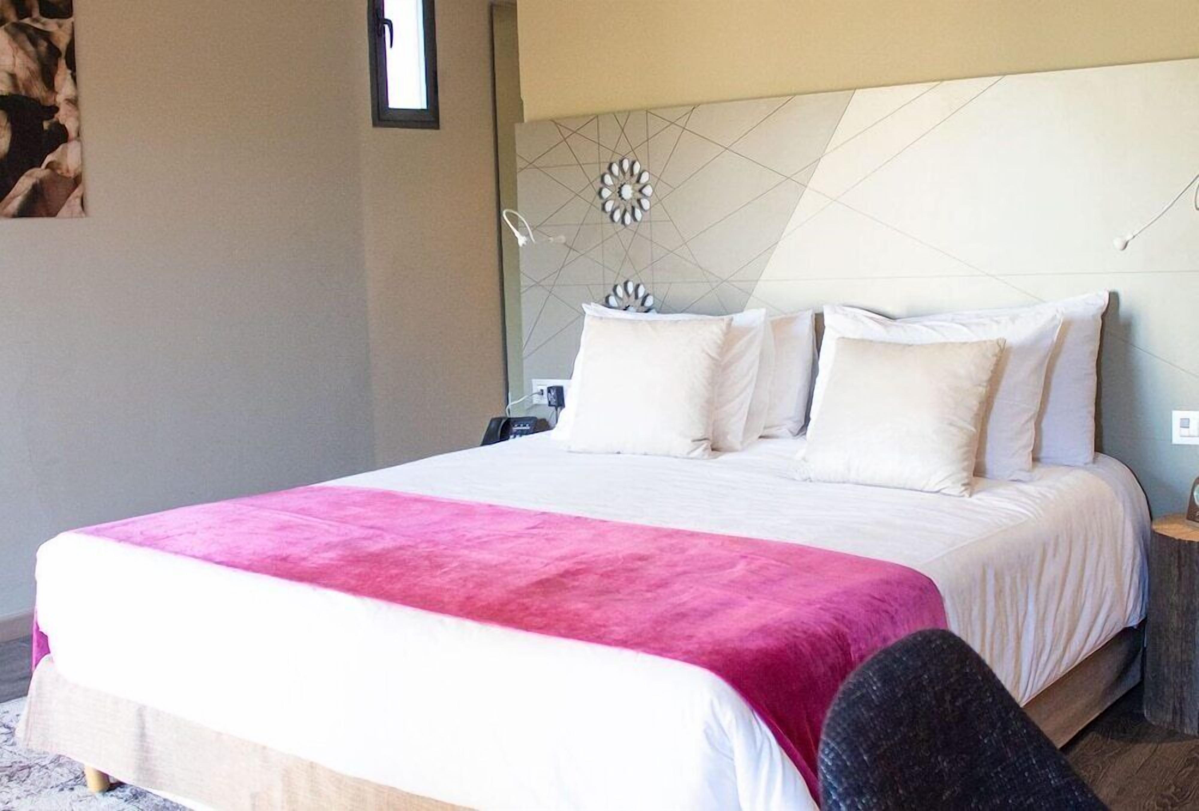 Habitación de hotel con una cama grande, una mesita de noche y un adorno en la pared.