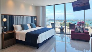 A modern hotel room with a large bed, a TV, and a balcony with a view of the sea. - Hotel Perla Spondylus (Manta)