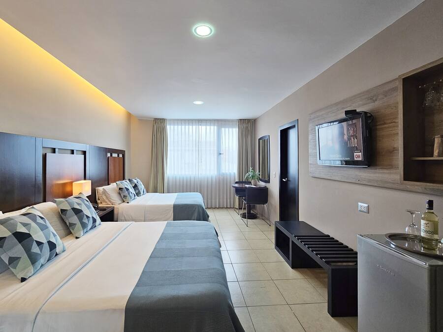 Une chambre d’hôtel avec deux lits, une télévision, un bureau et un mini-bar.
