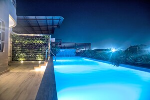 Una piscina al aire libre, sillones reclinables de piscina