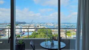 A balcony with a table and chairs, overlooking a marina with boats and a large cruise ship. - Hotel Perla Spondylus (Manta)