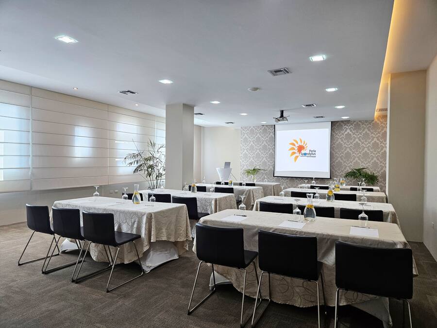 A conference room with tables set for a meeting, a projector screen, and a large window.