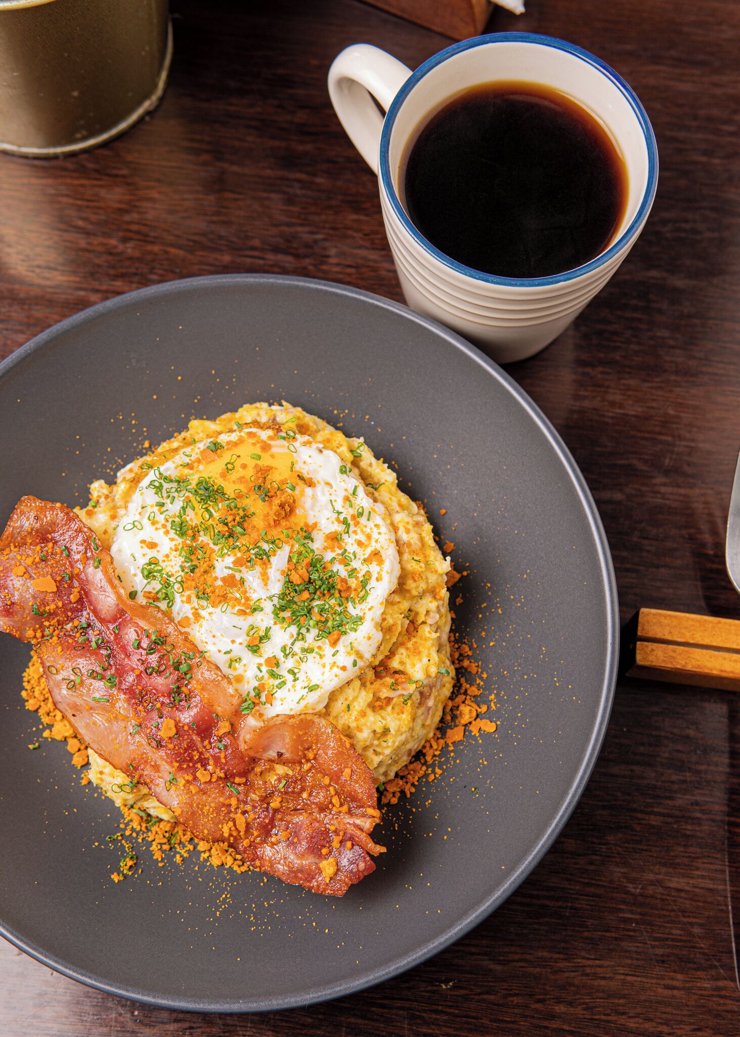 En tallerken med mad bestående af pocherede æg, bacon og en portion hash browns.