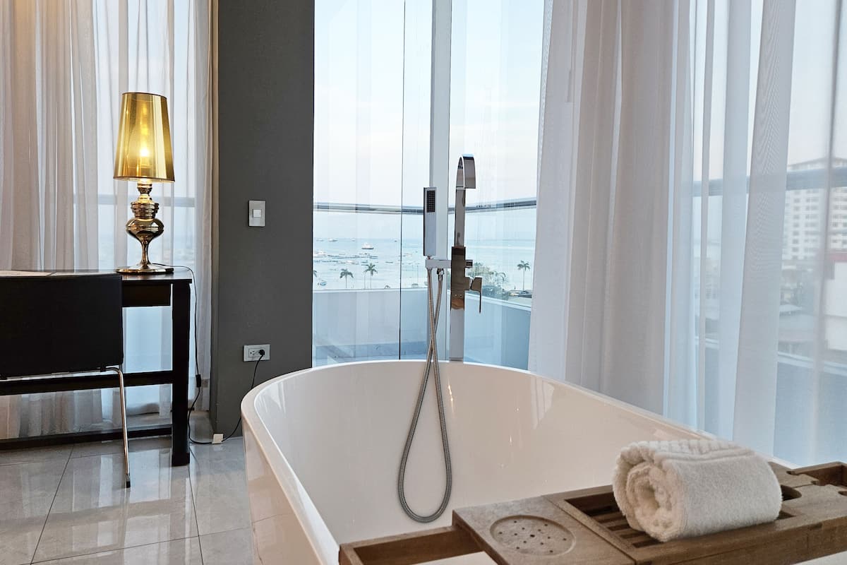 A modern bathroom with a freestanding bathtub, a wooden tray, and a towel.