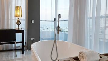 A modern bathroom with a freestanding bathtub, a wooden tray, and a towel.