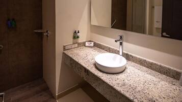 Un baño moderno con encimera de granito, un lavabo blanco y un espejo grande.