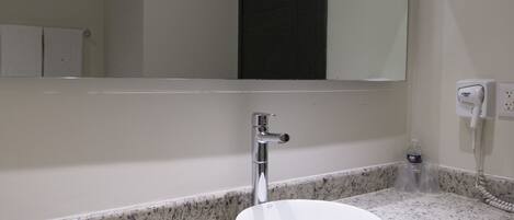 A bathroom with a white sink, a mirror, and a towel rack.