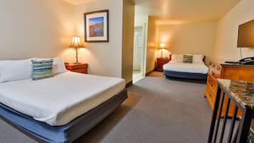 A hotel room with two beds, a desk, and a television.
