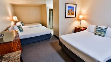 A hotel room with two beds, a desk, and a bathroom visible through an open door.