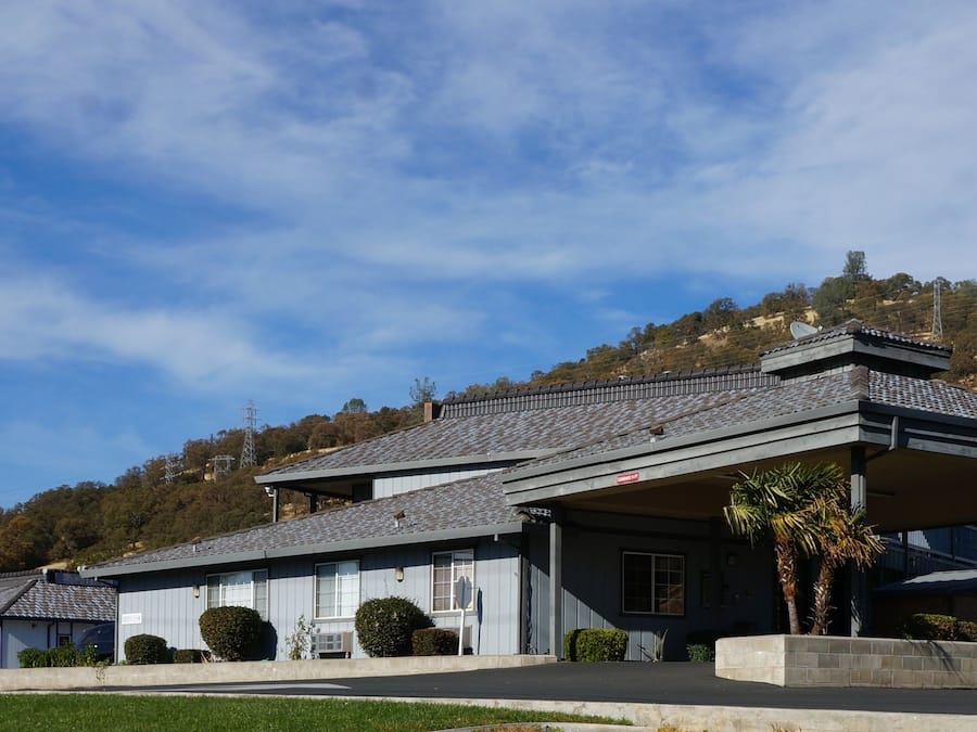 Un chalet doté d’un patio couvert, d’une enseigne indiquant « Lake Point Lodge », et d’un paysage vallonné en arrière-plan.