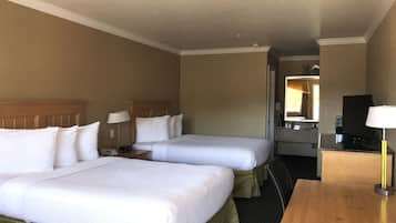 A hotel room with two beds, a desk, a TV, and a bathroom visible through an open door.
