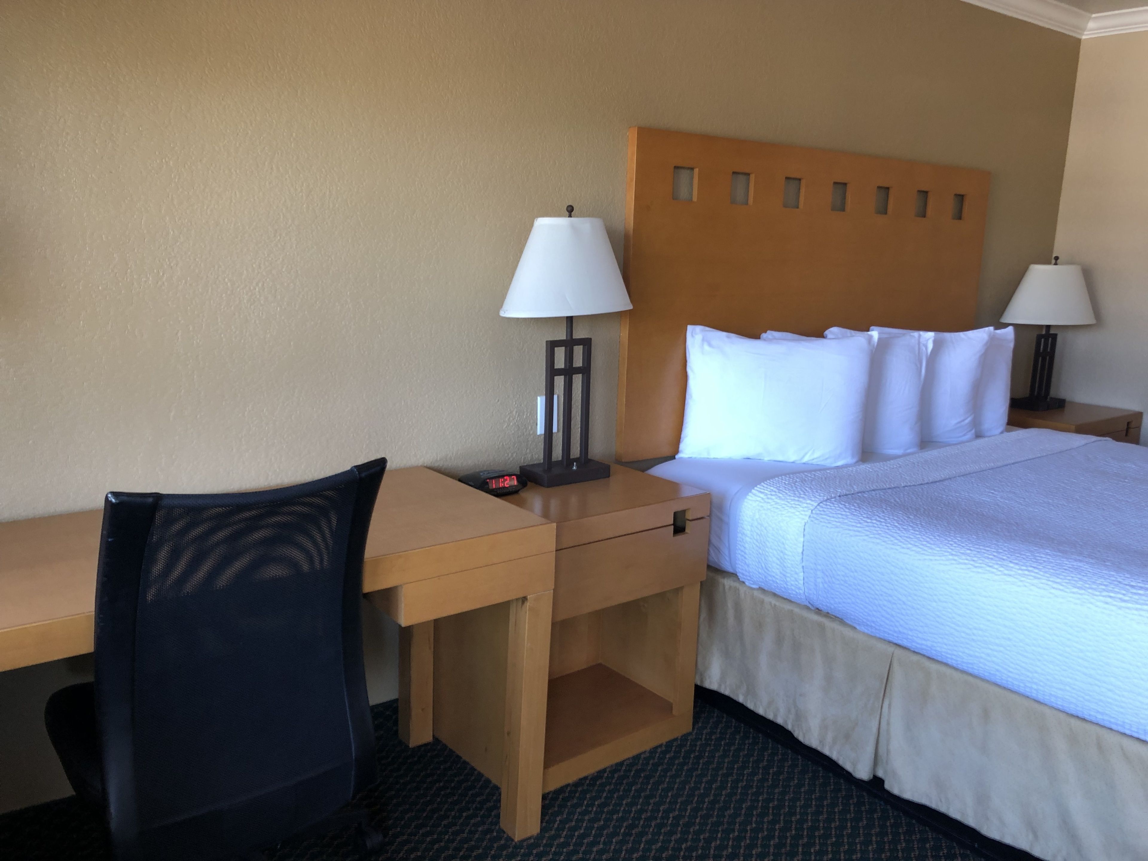 A hotel room with a bed, two bedside tables, a desk, and a chair.