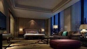 Ett hotellrum med en stor säng, en sittgrupp med soffa och fåtöljer, ett soffbord och ett stort fönster med utsikt.
