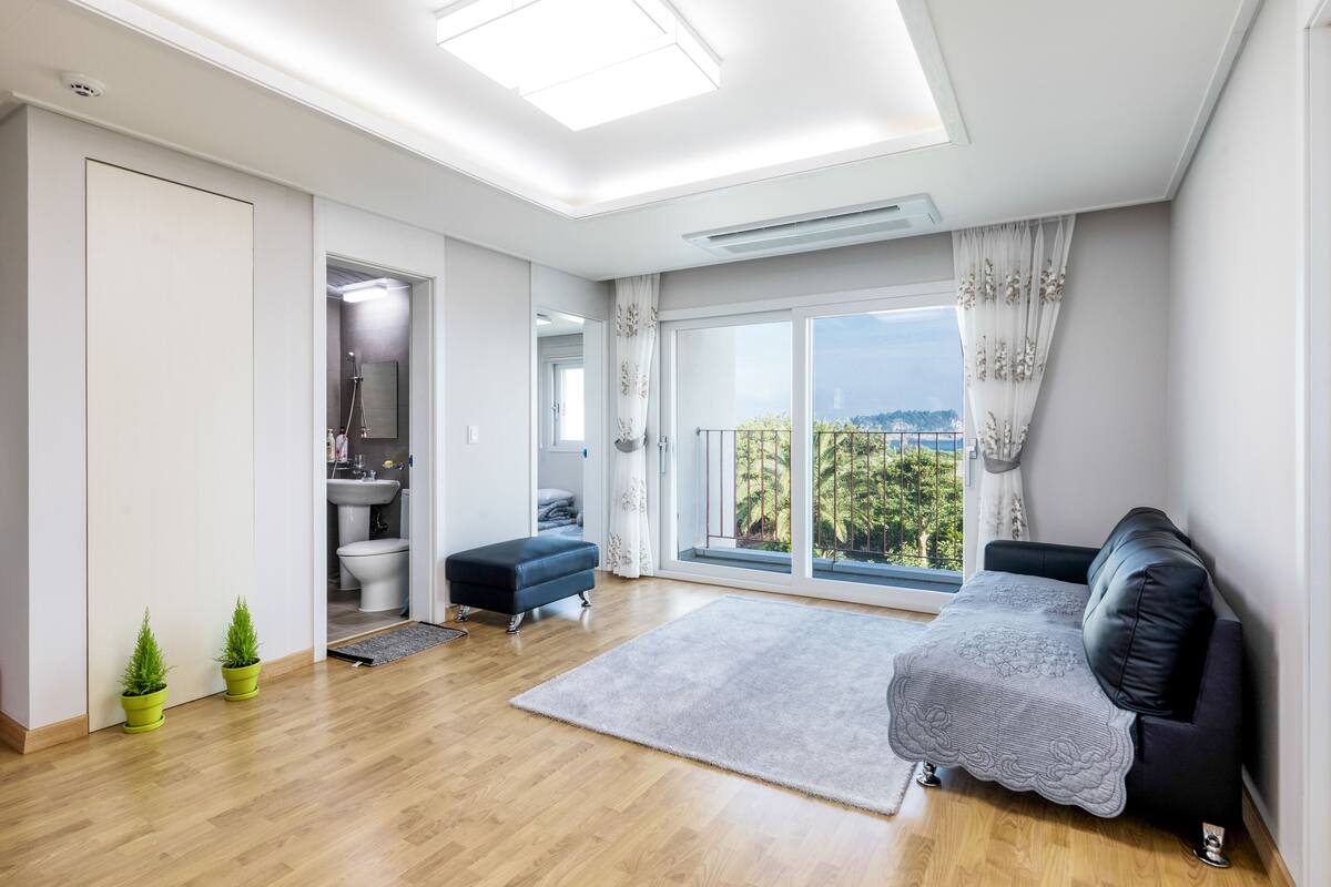 Un salon moderne avec une grande fenêtre, un canapé, une petite table et une plante en pot.