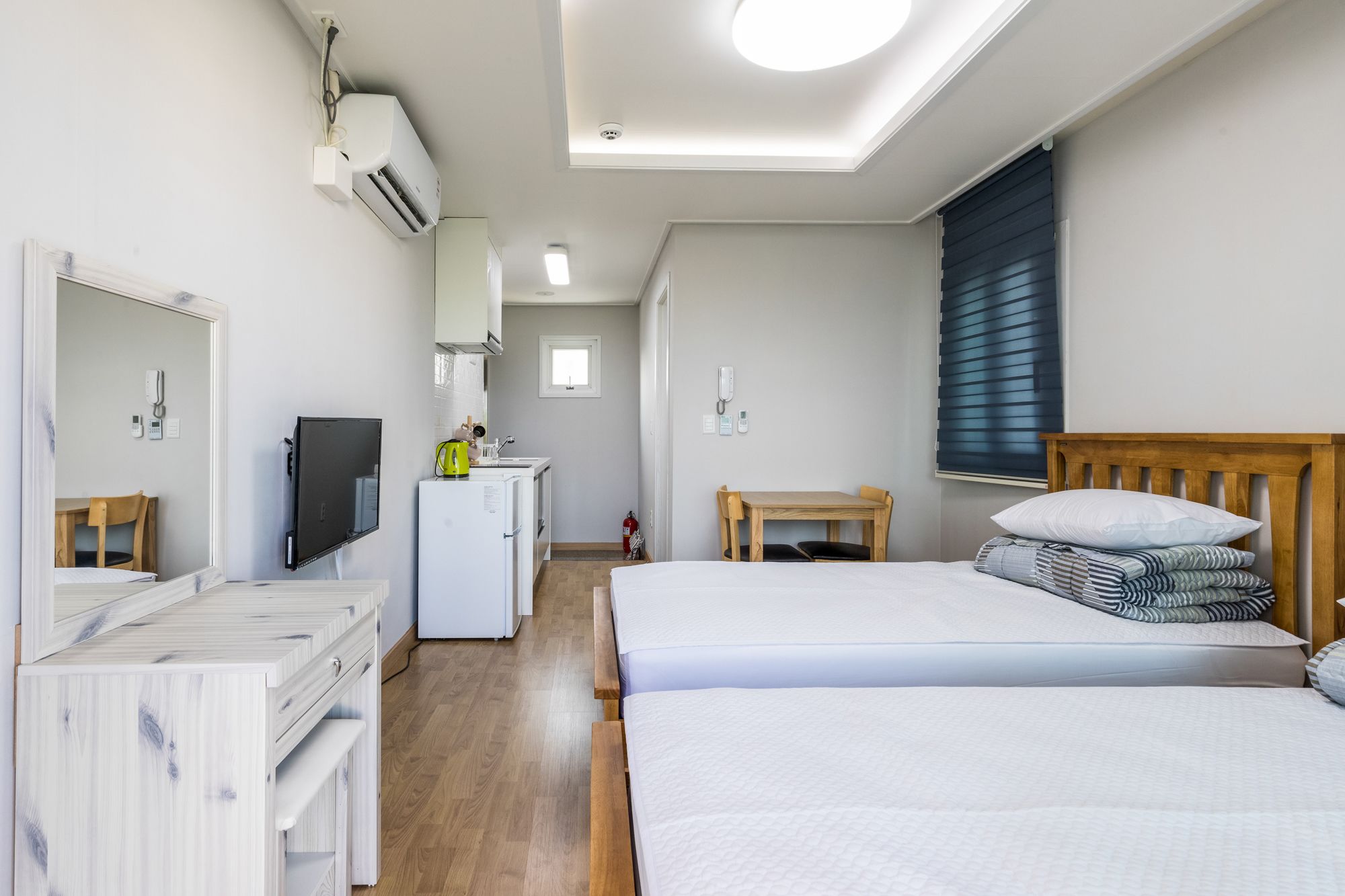 A hotel room with a bed, a desk, a small kitchenette, and a bathroom.