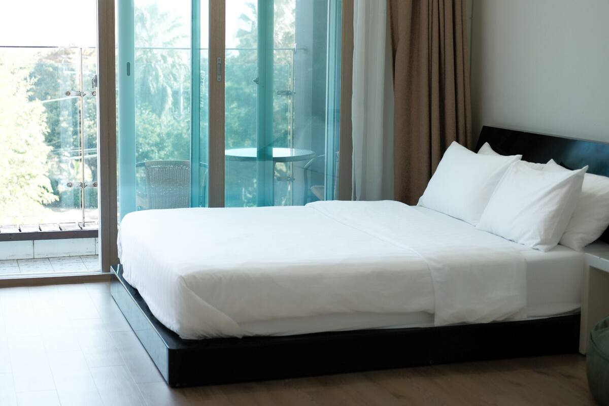 Een hotelkamer met een groot bed, een klein tafeltje en een balkon met een glazen deur.