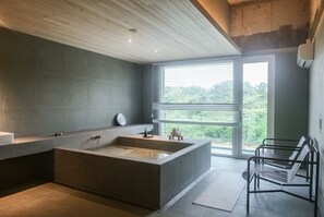 Une salle de bain moderne avec une grande baignoire, une fenêtre avec des stores et un banc.