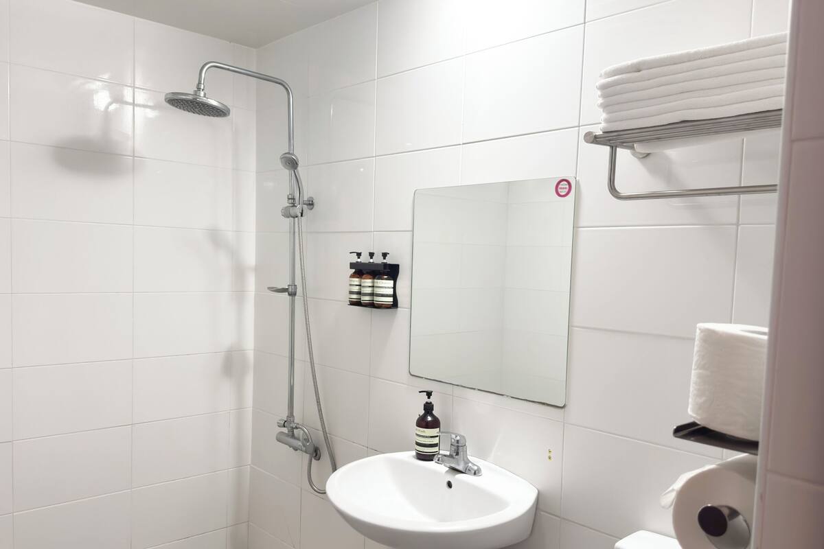 Een badkamer met een douche, wastafel, toilet en een spiegel.