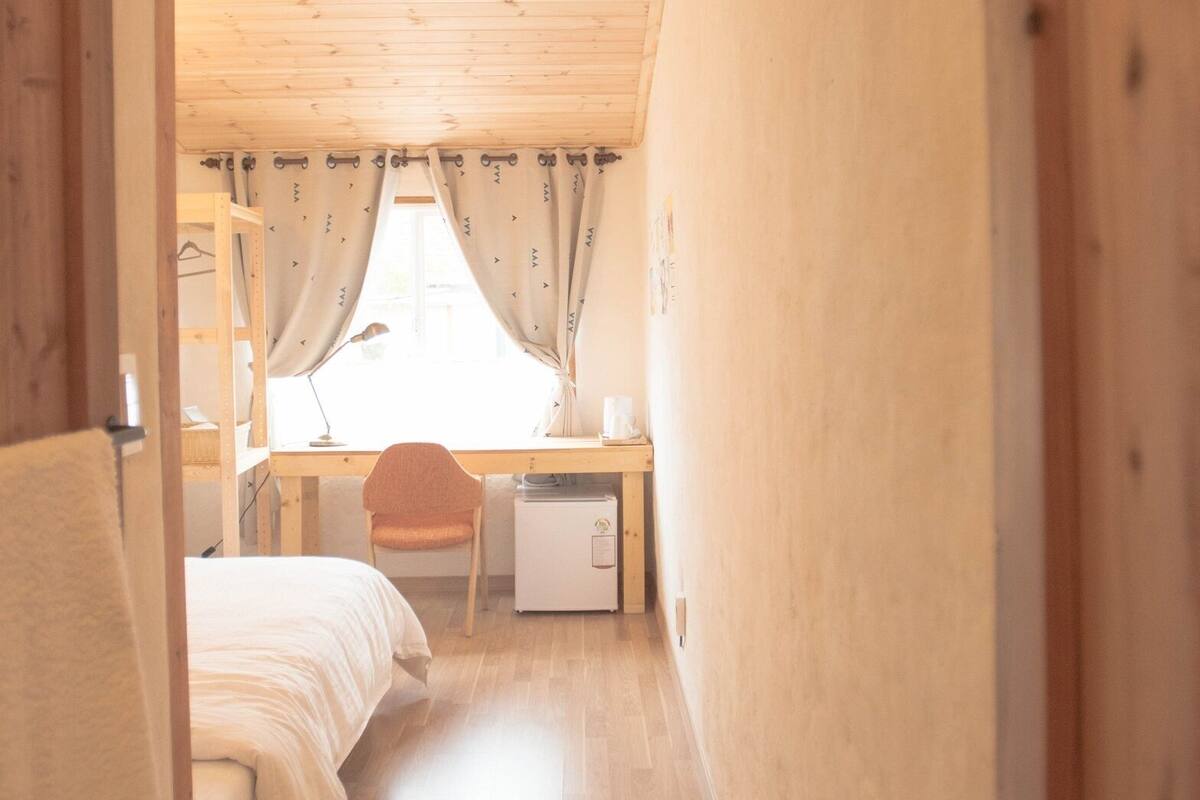 Un couloir étroit mène à une chambre qui contient un lit, un bureau et une chaise.