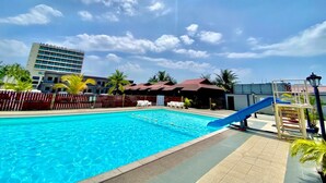 A swimming pool with a blue slide, palm trees, and a building labeled "Mercure Hotel" in the background. - Langgura Baron Resort (Langkawi)