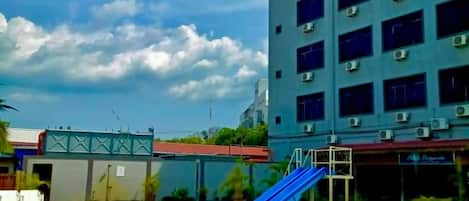A swimming pool with a blue slide, surrounded by a building with multiple windows and air conditioning units.
