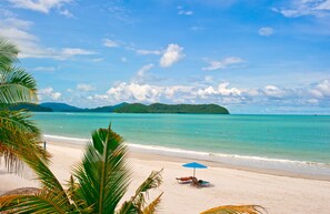 A beach with clear turquoise water, a sandy shore, and a distant island. - Langgura Baron Resort (Langkawi)