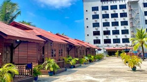 A row of wooden buildings with a large white building in the background. - Langgura Baron Resort (Langkawi)