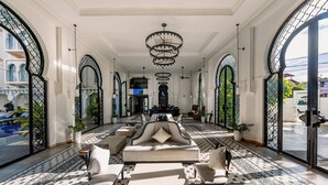 A spacious lobby with a central seating area, large arched windows, and a chandelier. - Sarai and Wander (Siem Reap)