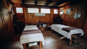 Eine Holzhütte mit zwei Betten, einem kleinen Tisch mit einer Mikrowelle und einem Fenster mit Blick auf Bäume.