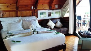 Ein Schlafzimmer einer Holzhütte mit einem Bett, einer Bank und einem Fenster mit Vorhängen.