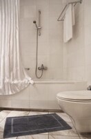 Un bagno con doccia, WC e porta asciugamani.