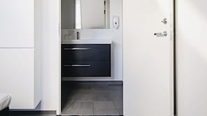 Een moderne badkamer met een wit wastafelmeubel, donkere lades en een spiegel.