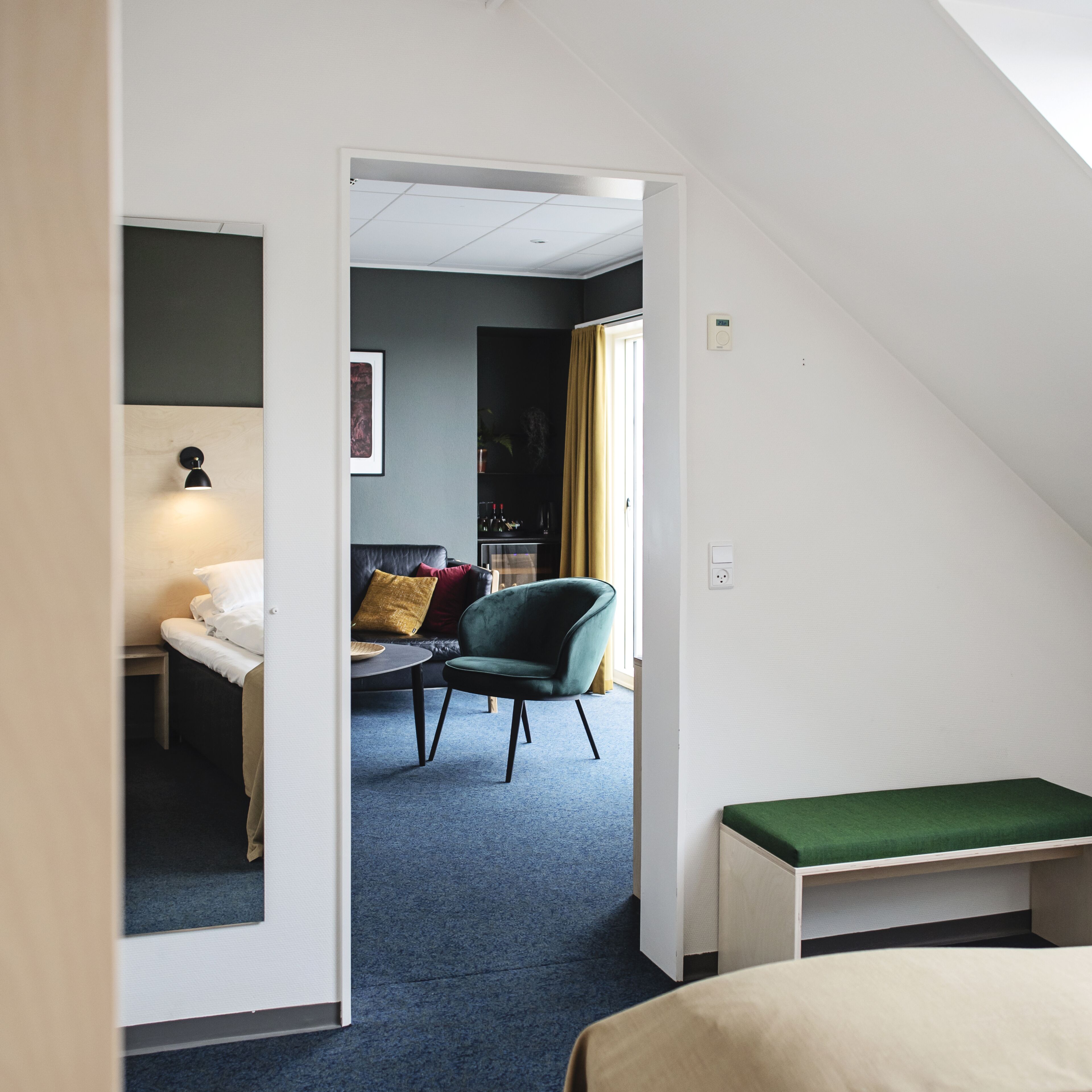 A modern hotel room with a bed, a desk, a chair, and a small table.