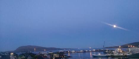 A coastal town at dusk with buildings, a dock, and a lighthouse.