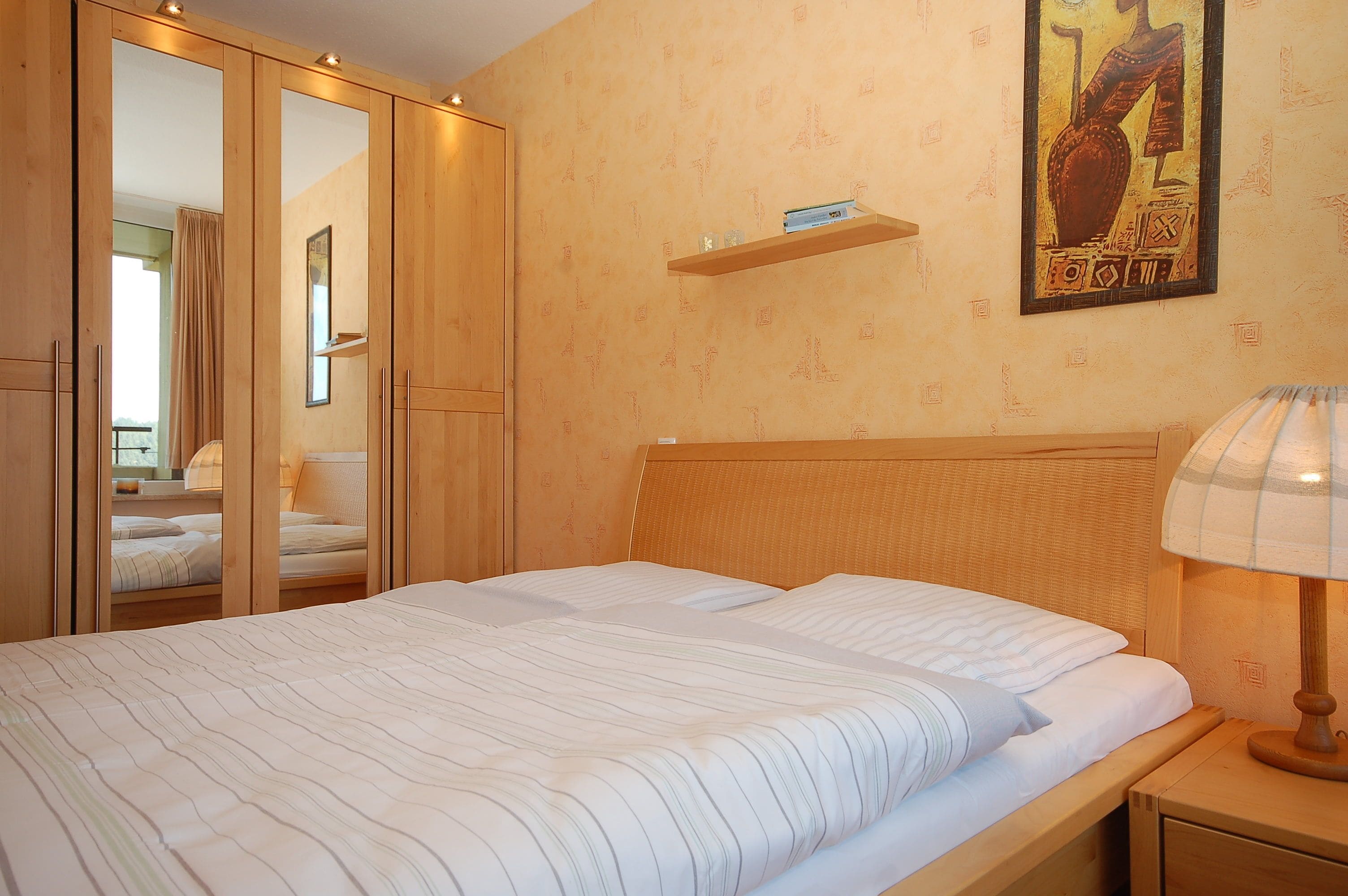 Ein Schlafzimmer mit einem Bett, einem Holzschrank und einem Nachttisch mit einer Lampe.