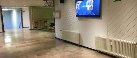 Un pasillo con una pantalla de televisión, un letrero que indica el Panorama Lounge y un letrero de salida de emergencia verde.