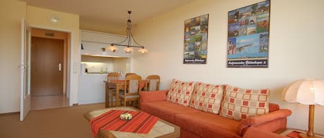 Una sala de estar con sofá, una mesa de centro y un comedor con sillas y una mesa.