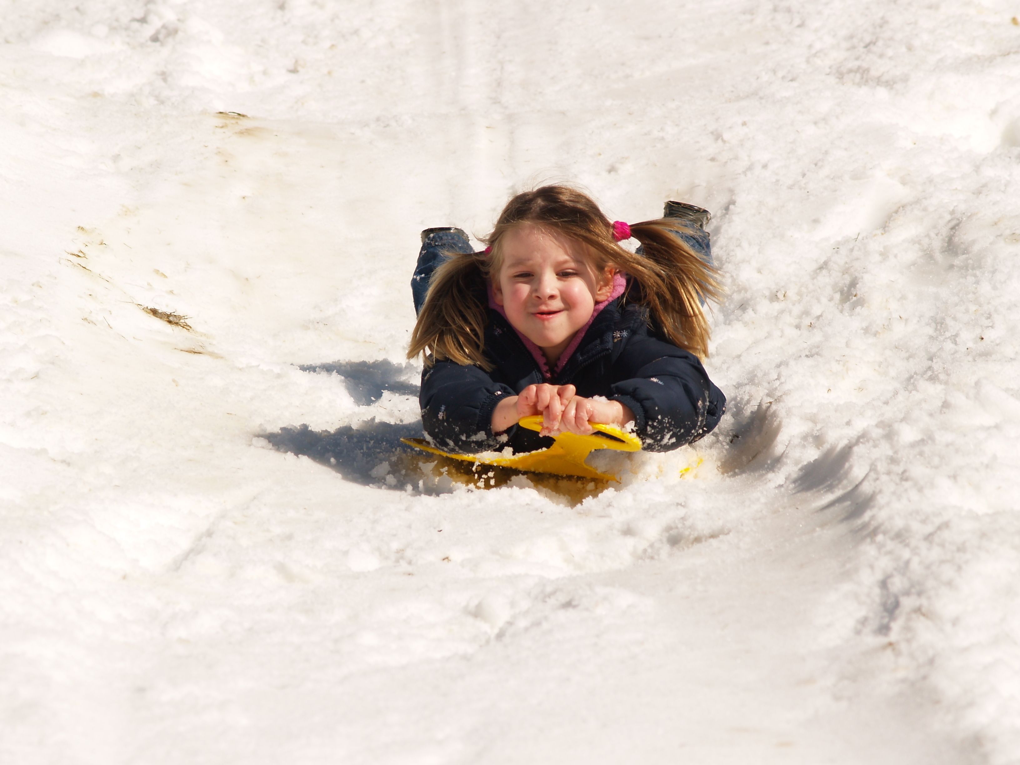 A child sledding down a snowy slope.