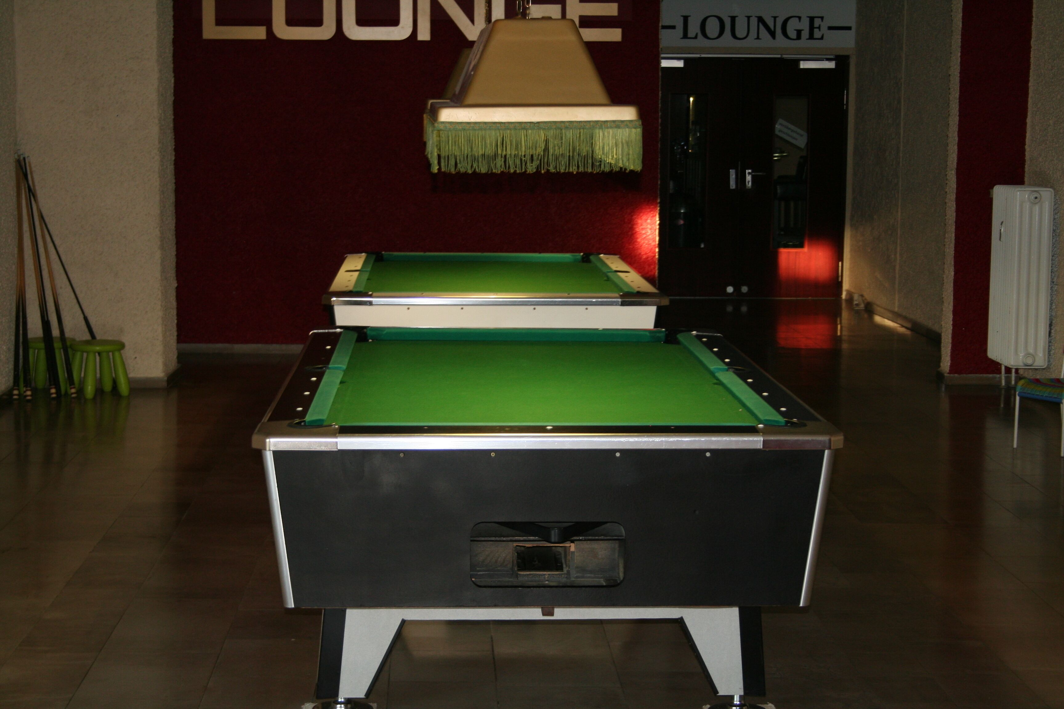 A pool table in a lounge area with a sign above it.