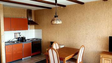 Una cocina compacta con gabinetes naranja, una estufa y un comedor con mesa y sillas.