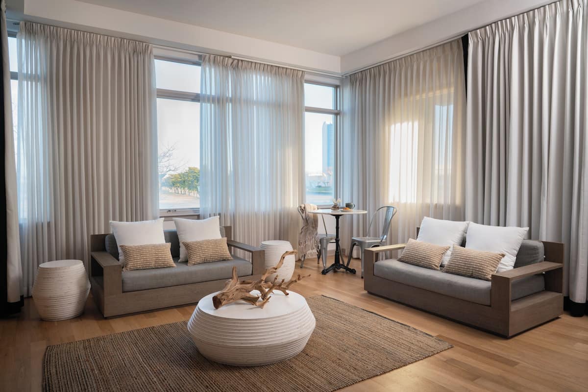 Ein modernes Wohnzimmer mit zwei grauen Sofas, einem runden Couchtisch mit Holzeinsatz und einem kleinen, runden Tisch mit Stühlen.