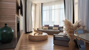 A modern living room with a sofa, a coffee table, and a TV mounted on the wall. - Bungalow Hotel (Long Branch)